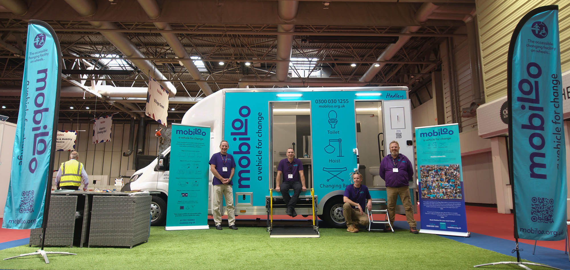 Mobiloo team posing in front of Mobiloo van at exhibition